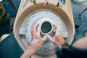 A woman potter works on a potter's wheel.