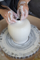 A woman potter works on a potter's wheel.