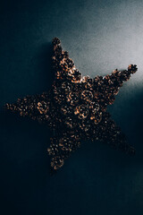 Beautiful Christmas decoration made of pine cones in the shape of a star on a dark background. 