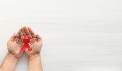 Concept World AIDS Day. Hands of man holding red ribbon on white background. Blood transfusion and donation. Hemophilia day. World Health Day. Layout. Copy space. Banner