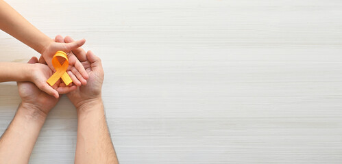 Hands of father and child hold orange ribbon on white background.Concept. World Multiple Sclerosis day. Leukemia cancer awareness. COPD and ADHD. Layout. Copy space. Banner.