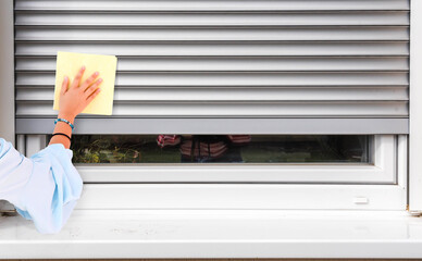 woman hand cleaning sunblind on white pvc window
