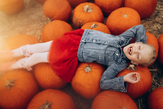 Happy girl lying on a pile of large pumpkins in the field. High quality photo