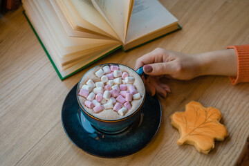 Girl's hand holds a cup with cocoa in a cozy cafe