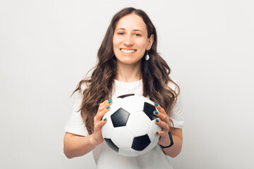 Wide smiling woman is holding a soccer ball and looking at the camera.