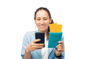 Happy smiling woman is checking on the phone her flight date while holding passport with tickets.