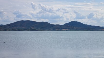 A wooden pole that emerges from the surface of Lake Trasimeno (Umbria, Italy, Europe) - 462886832