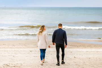 Loving couple relaxing on sandy beach. Love concept.Back view.Spring,autumn vacation.