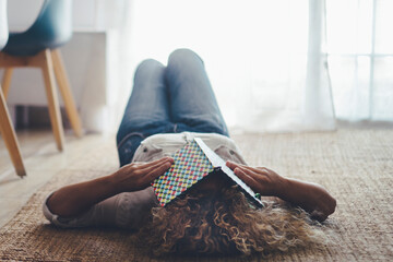 Woman lay down on the floor on carpet sleeping because tired with book to cover eyes. Female people asleep during the day in living room. Insomnia disease health concept