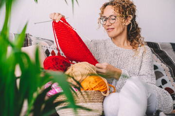 Happy pretty woman smile and admire her knit work wit red colorful wool. Female people enjoy indoor...