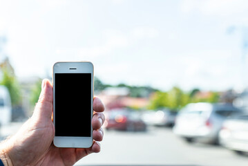Man using phone in car, GPS navigation ,blank space frame on smartphone in hand with blur image of traffic.