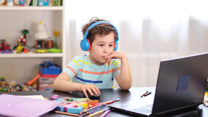 Learn on your schedule. Distance learning online education. A schoolboy boy studies at home and...