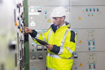 Man electrical engineer hold tablet monitoring electrical system in control room. Technician...