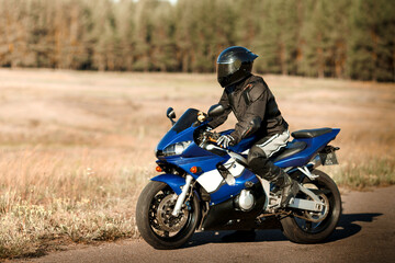 Biker in helmet and leather jacket racing on the road. Motorcyclist in gear, motorcycle driver looks, concept, active lifestyle