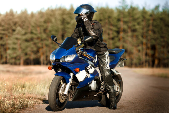 Biker man on a motorcycle in a leather jacket and helmet looks at the road