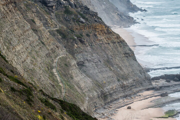 Majestic staircase embedded in steep coastal cliff leading to beach