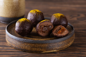 Obraz premium Orange and turmeric chocolate truffles in a plate. Sugar, gluten and lactose free, vegan.