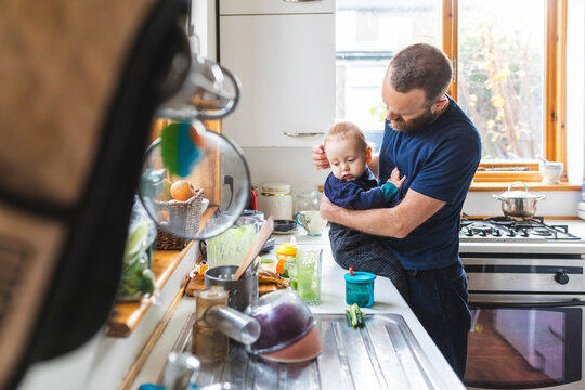 Man in the kitchen preparing food and cuddling his son