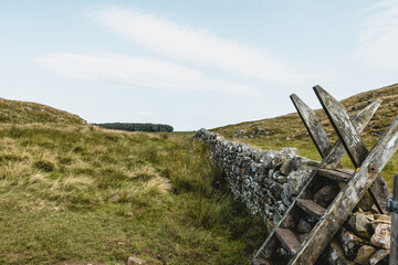 Traditional British stone wall with wooden ladder stile in countryside