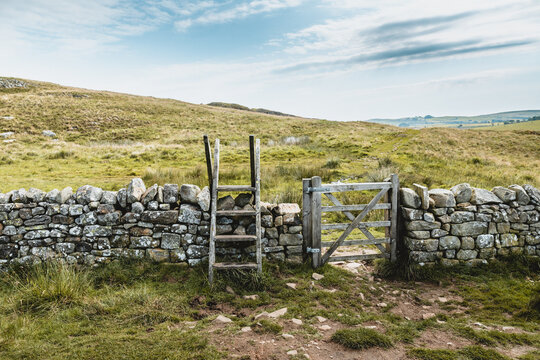 Traditional British stone wall with wooden ladder stile in countryside