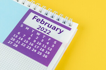 February 2022 desk calendar on yellow background.