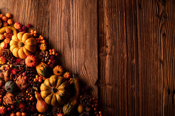 Autumn composition on a rustic wooden background. Decorative pumpkins, various leaves, pine cones, nuts. Orange, yellow, red  and brown aesthetics. 