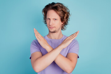 Portrait of handsome brown-haired guy showing ban sign prohibition isolated over turquoise color...