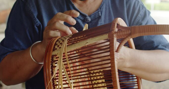 Cut in shot of Thai female farmer weave basket in traditional Thai art patterns to sell as extra income in countryside of Thailand.