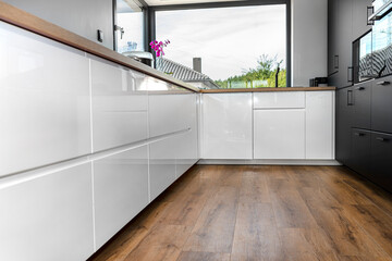 A modern kitchen with built in cabinets against the wall with white fronts, vinyl panels on the...