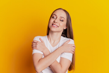 Obraz premium Close-up portrait of attractive lovely girl hugging herself comfort cozy dream isolated over bright yellow background