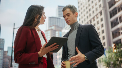 Confident Businesswoman Showing Financial Projections to Her Work Partner on Laptop Computer. Manager and Entrepreneur Discussing a Project Outside on a Street in Big City in Downtown.
