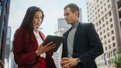 Confident Businesswoman Showing Financial Projections to Her Work Partner on Laptop Computer. Manager and Entrepreneur Discussing a Project Outside on a Street in Big City in Downtown.