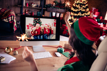 Photo of young woman santa helper talk camera online relatives greetings hold sparklers indoors...