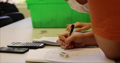 students reading and writing down data in form after engineering tests in laboratory. Mobile phone, calculator and worksheet on desk - Powered by Adobe