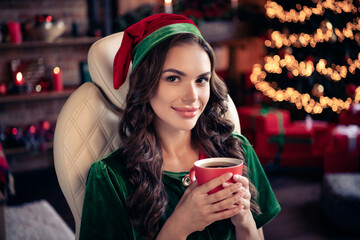 Portrait of attractive dreamy cheerful girl elf drinking latte beverage festal day at decorated home modern loft industrial interior indoors