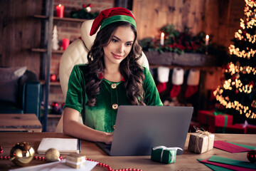 Photo of young woman serious santa helper elf sit desk work latop assistant xmas indoors inside...