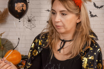 A lit lamp in the shape of a pumpkin in the hands of a woman, a decoration for the Halloween holiday.