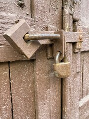 wooden painted door of brown color closed on two locks hanging