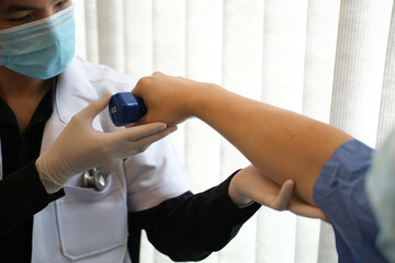 Photo of young physiotherapists provides assistance to male patients with elbow injuries at the rehabilitation center.
