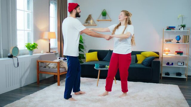 Lovely young couple man and woman in living room dancing romantic together and feeling relaxed thy speeding a good time together at home