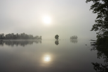 Mystic lake view with dense fog and sun.