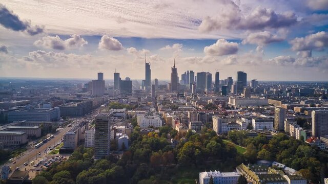 Morning forwards fly above city, hyperlapse of busy road and clouds flowing in sky. Skyline with tall modern office buildings. Warsaw, Poland