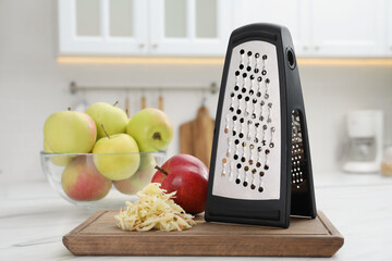 Grater and fresh ripe apples on white table in kitchen