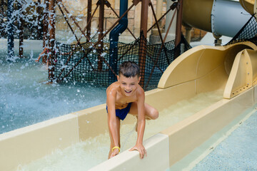 A happy boy of seven years old descends from the slides in the water park. Happy vacation vacation....