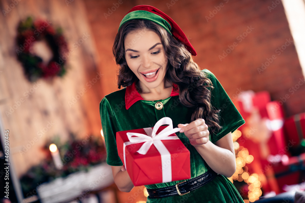 Poster photo of attractive beautiful young woman dressed green costume smiling opening christmas gift indoo