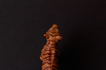 The concept tiger is the symbol of 2022. The tiger looks ahead. Plastic toy figure of a tiger on a black background. Top view. Place to place