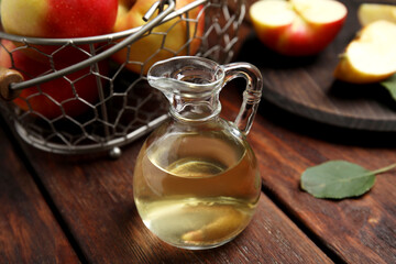 Natural apple vinegar and fresh fruits on wooden table
