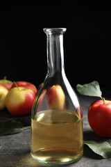 Natural apple vinegar and fresh fruits on grey table