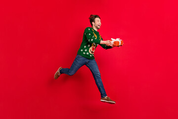 Fototapeta na wymiar Full size profile side photo of smiling crazy running man give christmas present celebration isolated on red color background