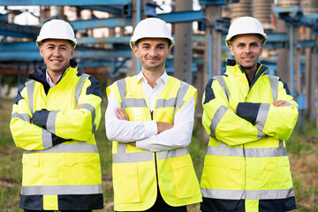 Group portrait of multiethnic industrial workers team consist of technicians, engineers, mechanic wearing helmet uniform looking camera. Industrial workers, electric industry, production concept
